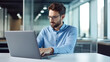 © halo - portrait of a businessman working on a laptop in a modern office, wearing a blue shirt and glasses.