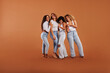 © Flamingo Images - Diverse women in jeans and white tops laughing against an orange background