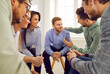 © Studio Romantic - Young man getting support from his friends. Group of happy young diverse people sitting in a circle and talking. Team of colleagues supporting their coworker during a meeting at work