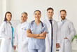 © Studio Romantic - Portrait of a happy confident successful team of young doctors in uniform looking cheerful at camera and smiling while standing in hospital or clinic. Medical staff and health care concept.