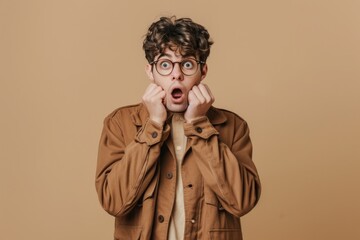 A man wearing a brown jacket and glasses holds his hands over his face, conveying sadness or distress