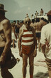 © yaqui_villegas - An elderly man stands on a sunny beach wearing a striped swimsuit, surrounded by many other beachgoers enjoying a lively day at the seashore under the bright sun.
