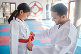 Martial arts, karate and achievement in studio for fitness, help and respect with orange belt. Sensei, student and celebration as people for self defense class, gratitude and discipline with support