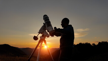 Wall Mural - Amateur astronomer looking at the evening skies, observing planets, stars, Moon and other celestial objects with a telescope just before sun down.