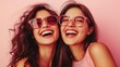 © Trusha - Two women wearing pink glasses and smiling. Scene is happy and cheerful. The women are posing for a photo, and their smiles suggest that they are enjoying themselves