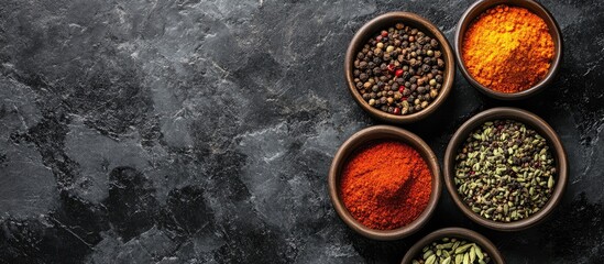 Poster - Assorted spices in bowls on a black concrete surface Top view copy space