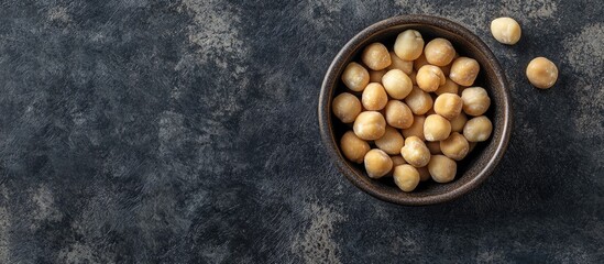 Leinwandbilder - Bowl with macadamia nuts on dark concrete Top view. with copy space image. Place for adding text or design