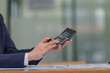 © Songsak C - Close-up hand holding and using a calculator.