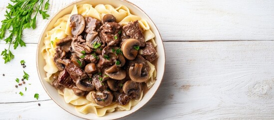 Wall Mural - Homemade creamy beef stroganoff with mushroom slices and onions served in a bowl captured from above on white wood with copy space alongside Selective Focus Focus on the dish