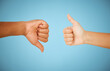 © KayJoint/peopleimages.com - Thumbs up, people or down hand gesture with for disagreement, approval and feedback on blue background. Positive, negative and icon closeup with okay sign, dislike and conflict in studio for vote