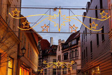 Charming Quedlinburg town evening street view illuminated with Christmas lights garlands Herrnhutter stars on historical half-timbered houses facade. Twilight Festive city in German