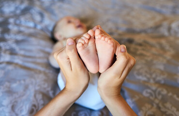 Mother, hands and baby feet in bedroom with family bonding for care, security and emotional comfort of nurture. Person, infant and foot for gentle touch, connection and growth development at house