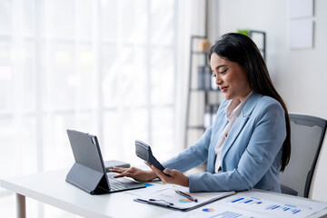 A woman is sitting at a desk with a laptop and a calculator