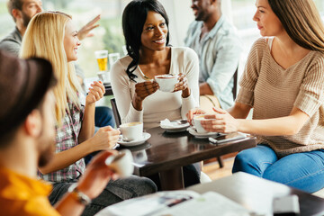 Diverse young women drinking coffee in busy cafe