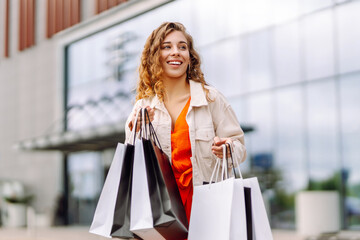 Wall Mural - Pretty young woman walking down with shopping bags on city street.  Sale, purchases, shopping, lifestyle concept.