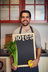 Wall Mural - Man, portrait and blackboard with groceries for health, nutrition or vegan diet for wellness. Male person, vegetables and smile in kitchen for cooking with food or recipe notes to prepare home dinner