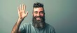 © vxnaghiyev - A young wild bearded man is smiling joyfully and cheerfully waving his hand to welcome you or bid farewell against a flat wall. with copy space image. Place for adding text or design