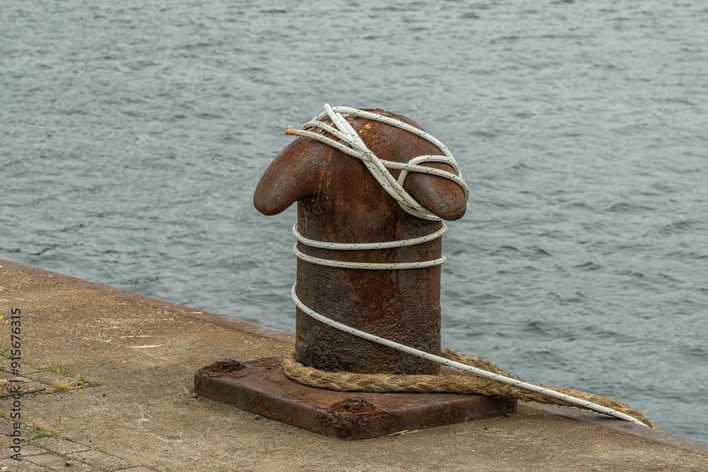metal rusty bollard with rope stretched around it