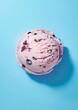 © NeuroCake - Top view of a single scoop of strawberry ice cream with chocolate chips on a blue background. Dessert and summer treat concept. Banner with copy space for ice cream shop advertising and menu.