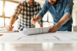 © Sunday Cat Studio - Two men collaborating on architectural plans in a bright workspace, focusing on detailed drawings and design elements.