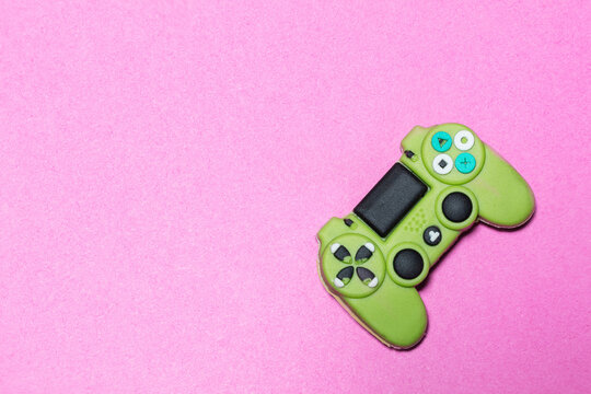 Green video game controller on fuchsia background. Pop culture and digital entertainment. Joystick. Image with copy space