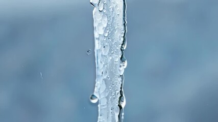 Aufkleber - A thick icicle slowly cracking and separating from its frozen surface dripping water as it falls.