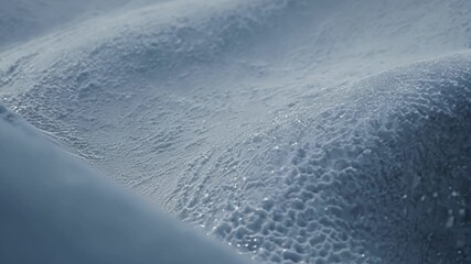Aufkleber - The camera slowly moves closer to the ground revealing a fascinating closeup of the intricate layers and textures of snow drifts formed by the wind.
