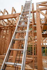 Wall Mural - Interior new house construction at wood framing stage, aluminum extension ladder propped up on 2nd floor support truss beams
