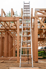 Wall Mural - Interior new house construction at wood framing stage, aluminum extension ladder propped up on 2nd floor support truss beams
