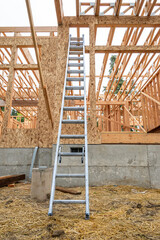 Wall Mural - Exterior new house construction at wood framing stage, aluminum extension ladder propped up against back wall, early days on residential job site
