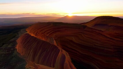 Poster - A timelapse of a sunset over rolling hills with exposed rock strata showcasing the changing colors and shadows of the layered rocks as the light shifts.