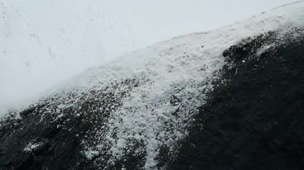 Poster - Closeup footage of a white powdery substance covering the surface of a dark jagged rock gradually revealing itself to be a of delicate pale lichen.
