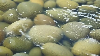 Aufkleber - An extreme closeup of a handful of pebbles revealing the intricate patterns and colors of each individual stone as the water glides over them.