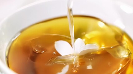 Poster - A single white petal falling gracefully into a cup of tea creating a peaceful and delicate scene.