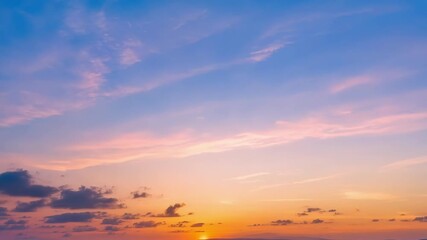 Aufkleber - The sky changing from a bright blue to a soft pastel pink and orange as the sun dips below the horizon.