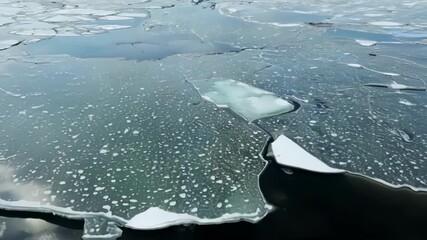 Aufkleber - A birds eye view of the ice slowly melting and shifting revealing the dark murky water underneath.