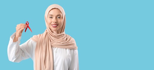 Poster - Female Muslim doctor with red ribbon on blue background. AIDS awareness concept