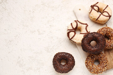 Board with sweet chocolate donuts on light grunge background