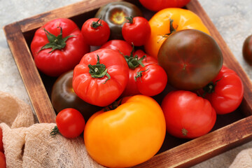 Canvas Print - Wooden box with different fresh tomatoes on grey background, closeup