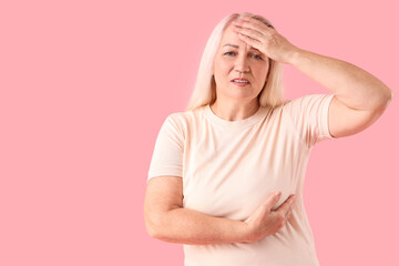 Wall Mural - Mature woman suffering from breast pain on pink background. Cancer awareness concept