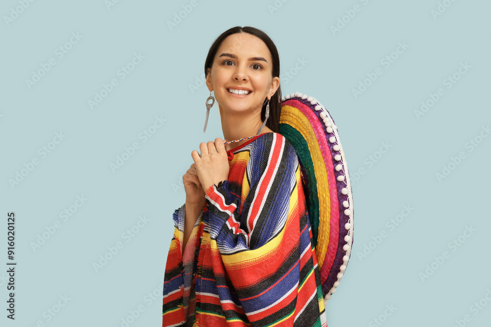 Beautiful young woman with sombrero hat on blue background
