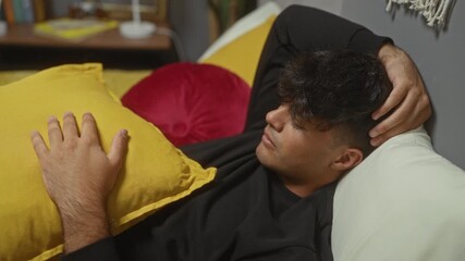 Canvas Print - A young hispanic man rests comfortably on a bed in a cozy bedroom, with his head on a pillow and hand relaxed, capturing serene indoor relaxation.