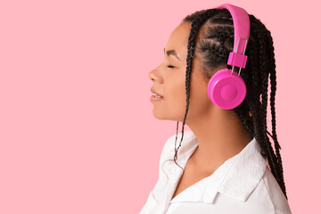 Poster - Young African-American woman listening to music on pink background