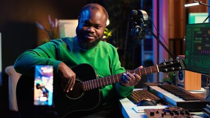 Leinwandbilder - Guitarist instructor hosting guitar lessons online using a mobile phone, recording tutorial for master class. Artist musician explains acoustic instrument accords, assistance for beginners. Camera A.