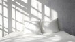 © Prime Stox - White pillow on a plain white bed with soft natural light, minimalistic background
