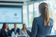 © BetterPhoto - Professional woman giving a presentation to a blurred audience in a modern office setting, highlighting leadership and communication skills.