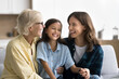 © fizkes - Joyful young mom and senior grandma cuddling kid girl, tickling child, laughing, giggling, enjoying family leisure, close relationship. Happy girls and women of three generations having fun at home