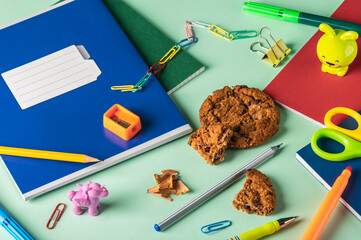 Wall Mural - Notebooks, pencils, a sharpener and other school stationery, cookies on a green background. Organization of a workplace. Selective focus.