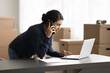 © fizkes - Woman talk on phone, check orders use laptop working in warehouse, ordering delivery services, makes calls to supplier, communicate with colleagues, coordinate workflow tasks or address urgent matters