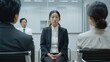 © bird_saranyoo - A stressed-looking Asian woman is being interviewed by a board of directors in a conference room.